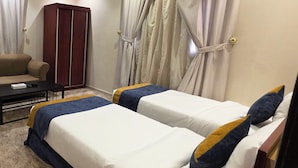 Ein Hotelzimmer mit zwei Betten, einem Schlafsofa, einem Schreibtisch und einem Kleiderschrank.