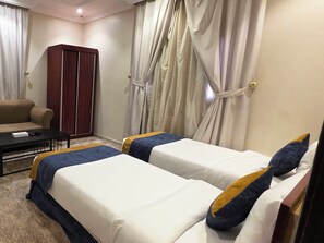 A hotel room with two beds, a sofa, a desk, and a wardrobe. - High Selection Serviced Apartments (Madinah)