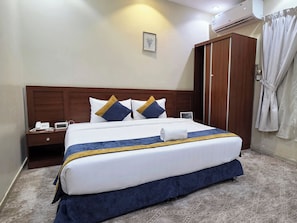 A hotel room with a bed, bedside table, and an air conditioning unit.