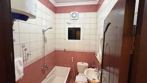 Ein Badezimmer mit Badewanne, Toilette, Waschbecken und einem Fenster.