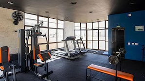 Un gimnasio con equipo de ejercicio, ventanas amplias y una pared azul.