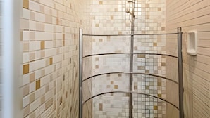 Una ducha con pared de azulejos y suelo de madera.
