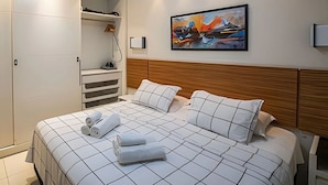 Una habitación de hotel con cama, armario y un cuadro en la pared.