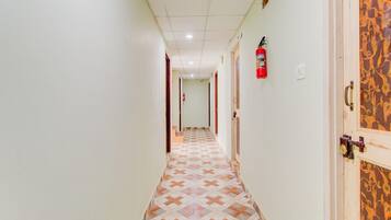 A hallway with patterned flooring, a fire extinguisher mounted on the wall, and a door with a decorative panel.