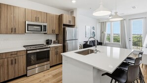 Een moderne keuken met houten kasten, roestvrijstalen apparatuur en een centraal kookeiland met zitplaatsen.