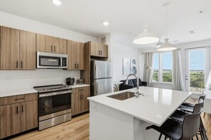 Una cocina moderna con armarios de madera, electrodomésticos de acero inoxidable y una isla central con asientos.