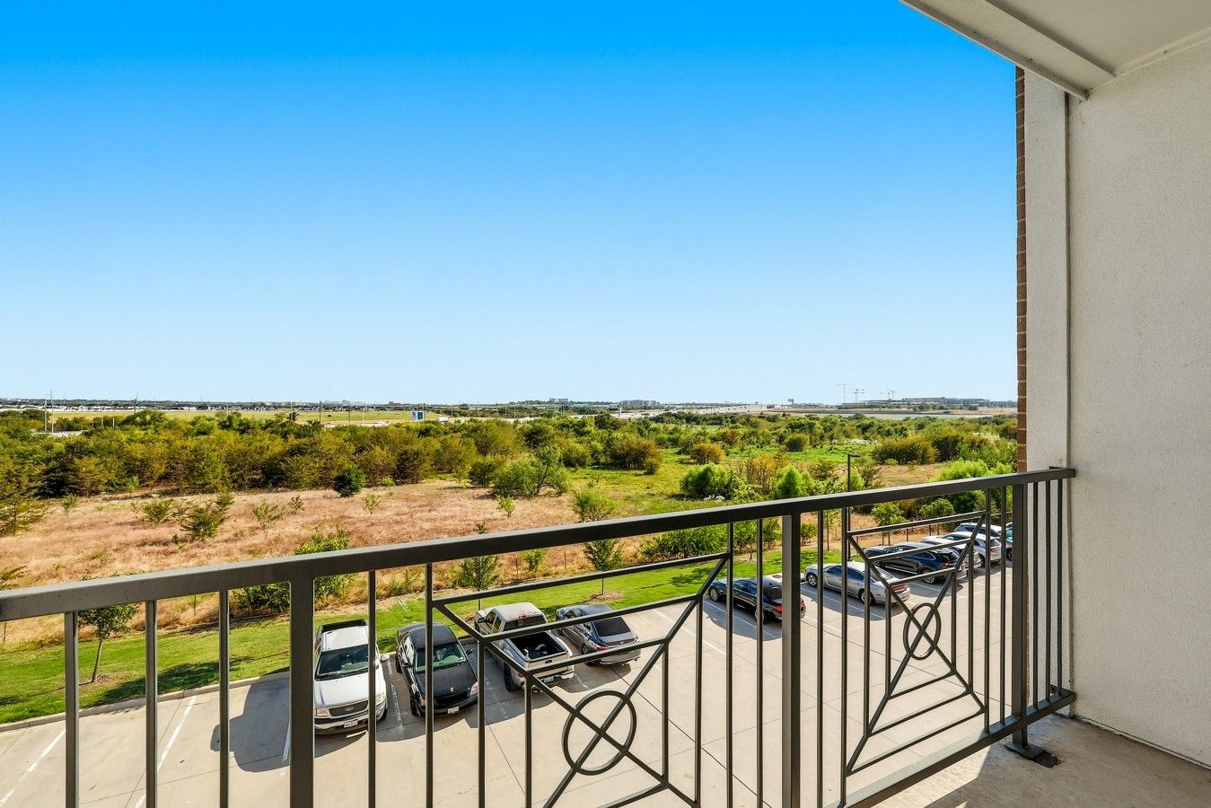 Ein Balkon mit Blick auf einen Parkplatz und die entfernte Landschaft.