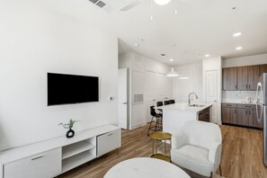 Una sala de estar moderna con un televisor de pantalla plana, un sofá blanco y una mesa de centro.