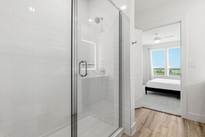Un baño moderno con cabina de ducha de vidrio, un cabezal de ducha visible y un ventanal que ofrece vistas al exterior.