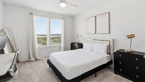 Een slaapkamer met een bed, een bureau, een stoel, een dressoir en een plafondventilator.