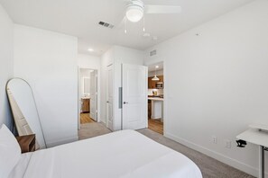 Una camera da letto con un letto, una ventola a soffitto e vista sulla cucina.