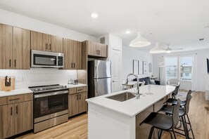Una cocina moderna con armarios de madera, electrodomésticos de acero inoxidable y una isla central con taburetes de bar.