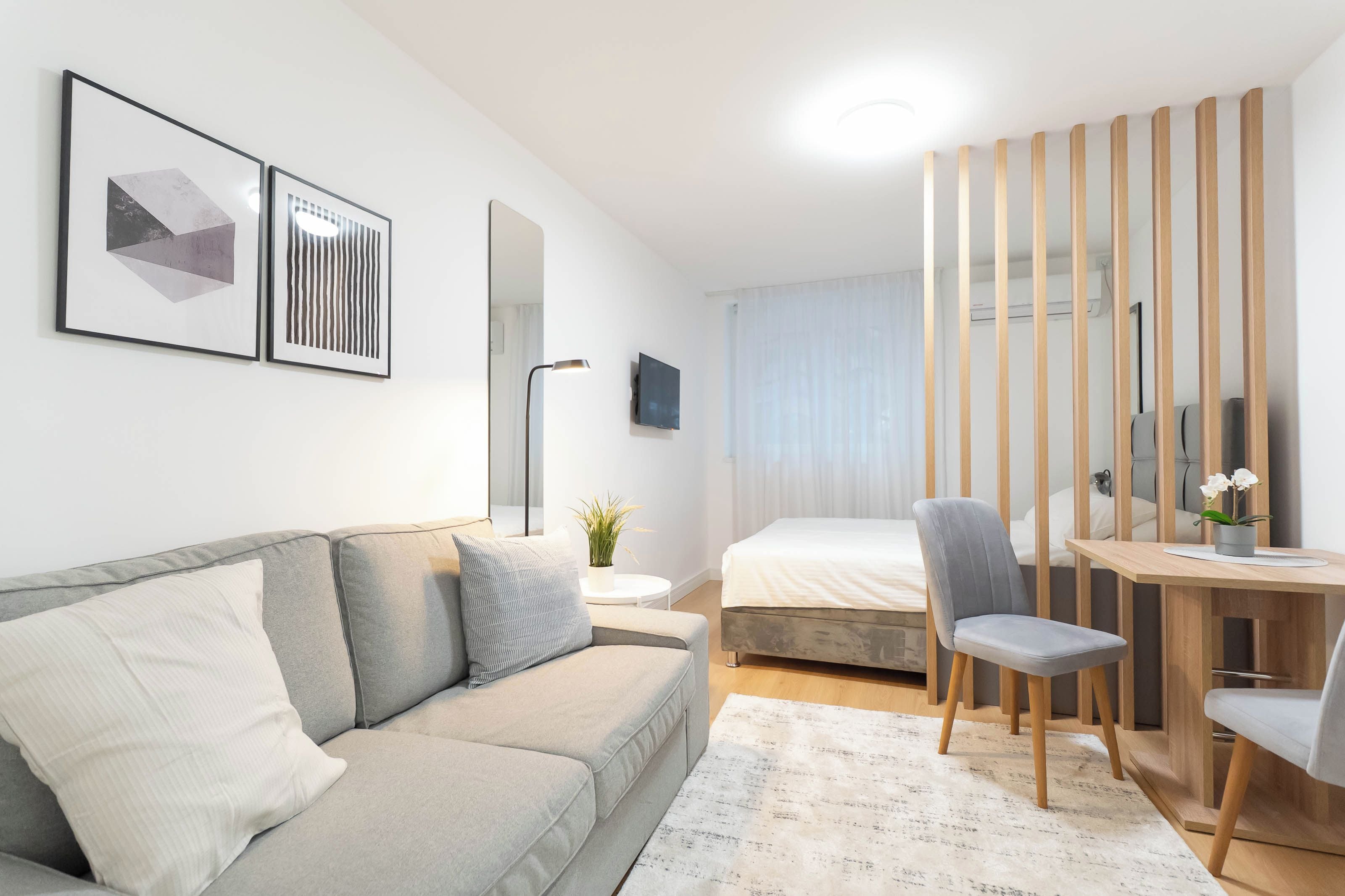 Una habitación de hotel moderna con sofá, cama, escritorio y televisión.