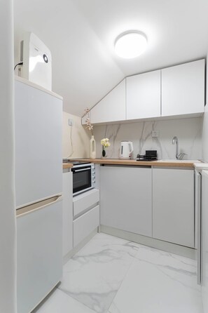 A modern kitchen with white cabinetry, a built-in oven, a microwave, and a coffee maker. - BeoVibe Studio Belgrade (Beograd)