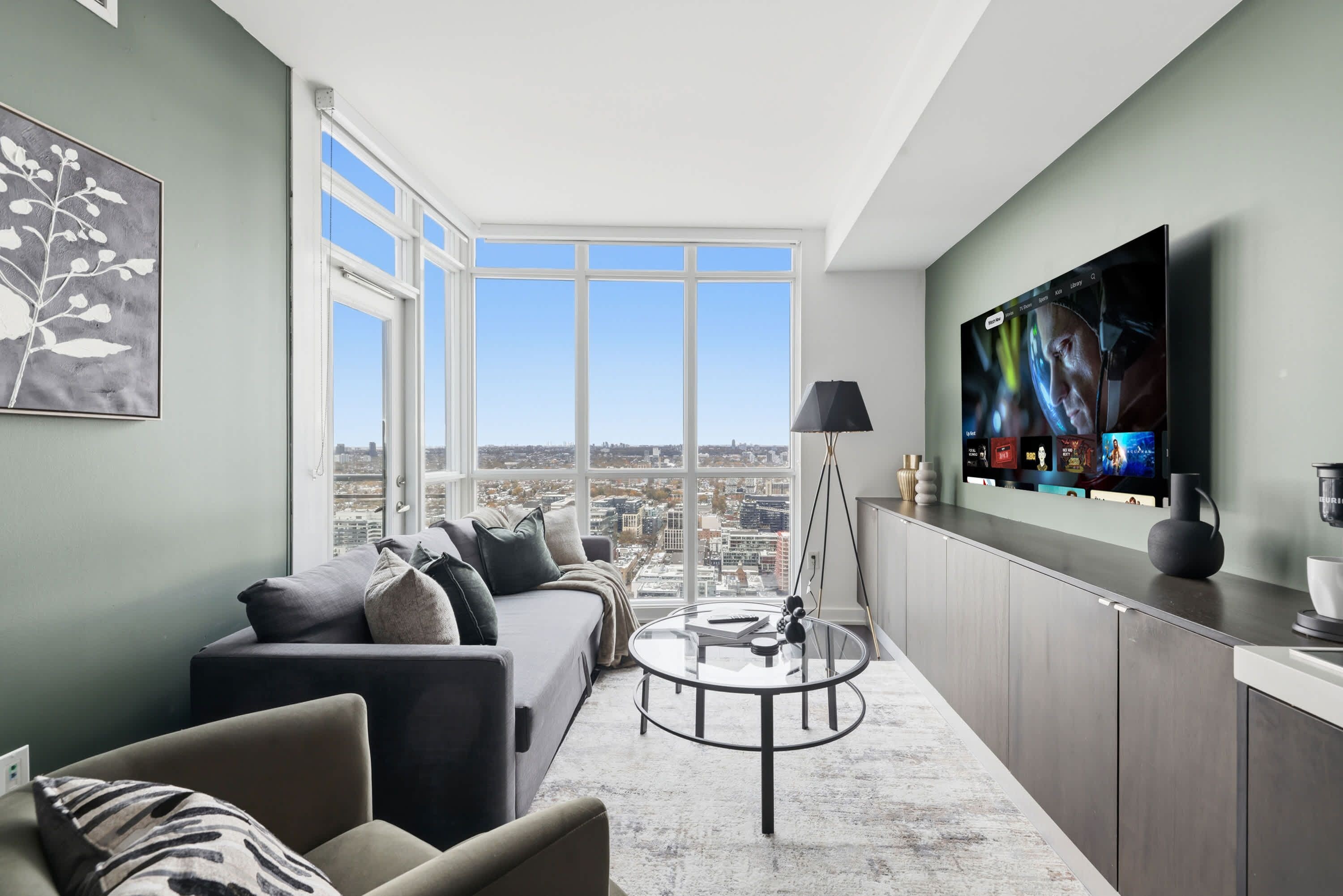 A modern living room with a sofa, a coffee table, and a TV mounted on the wall.