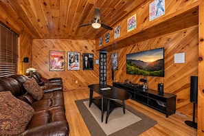 Ein gemütliches Wohnzimmer mit Ledersofa, Couchtisch, Fernseher und Bücherregal.