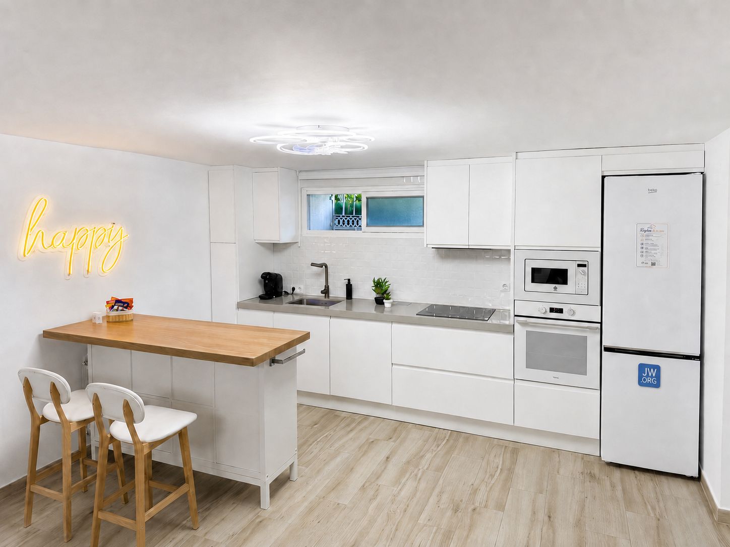 A modern kitchen with white cabinetry, a wooden countertop, and a neon sign.