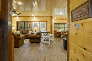 A wooden cabin interior with a living area, dining space, and a 'Welcome Home' sign. - 8BR*Sleeps 22*Pool*Game Room*Hot Tub*Mins to PF (Pigeon Forge)