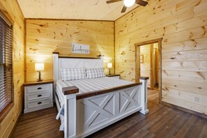 A wooden bedroom with a bed, bedside tables, and a ceiling fan. - 8BR*Sleeps 22*Pool*Game Room*Hot Tub*Mins to PF (Pigeon Forge)
