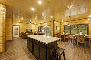 A log cabin interior with a kitchen, dining area, and living room. - 8BR*Sleeps 22*Pool*Game Room*Hot Tub*Mins to PF (Pigeon Forge)