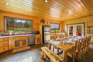 Een houten hut met een keuken, een eethoek en grote ramen.