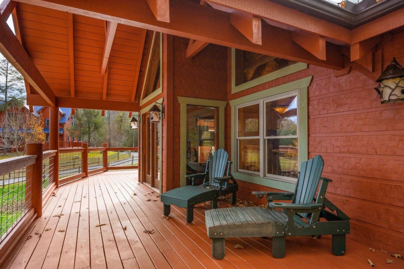 A wooden deck with Adirondack chairs and a covered porch area.