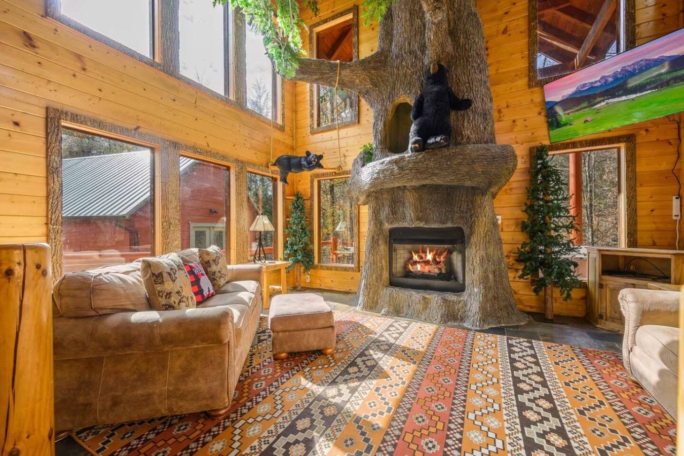 A cozy cabin interior with a fireplace, wooden walls, and a large window.