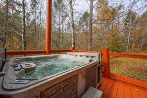 Ein Whirlpool auf einer Terrasses mit Holzgeländer, umgeben von Bäumen.