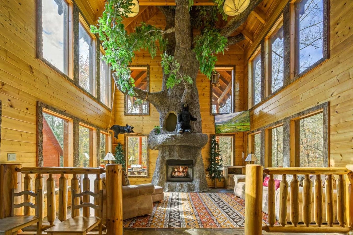 L’intérieur d’une cabane en rondins, avec un grand arbre servant de pièce maîtresse, une cheminée et un coin salon confortable.