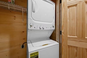 A white washing machine with a control panel, a yellow energy guide sticker, and a wooden wall. - 4BR Pool Cabin w/Hot Tub*Fire Pit*Games*Privacy! (Sevierville)