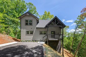 A two-story house with a balcony, surrounded by trees. - 4BR Pool Cabin w/Hot Tub*Fire Pit*Games*Privacy! (Sevierville)