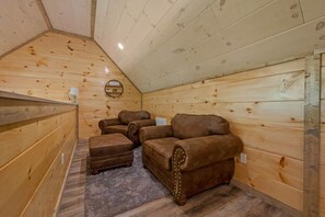 A wooden cabin with a sloped ceiling, three leather armchairs, and a small rug. - 4BR Pool Cabin w/Hot Tub*Fire Pit*Games*Privacy! (Sevierville)