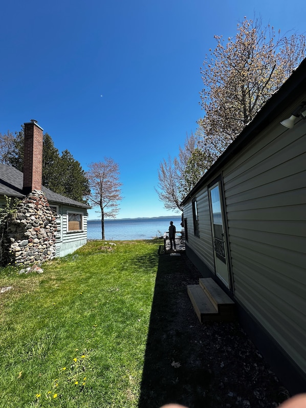 A cabin with a stone wall, a wooden deck, and a view of a lake.