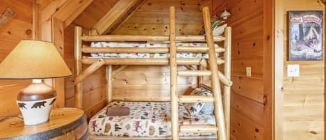 Un lit superposé en bois avec une échelle, une lampe et une affiche accrochée au mur.