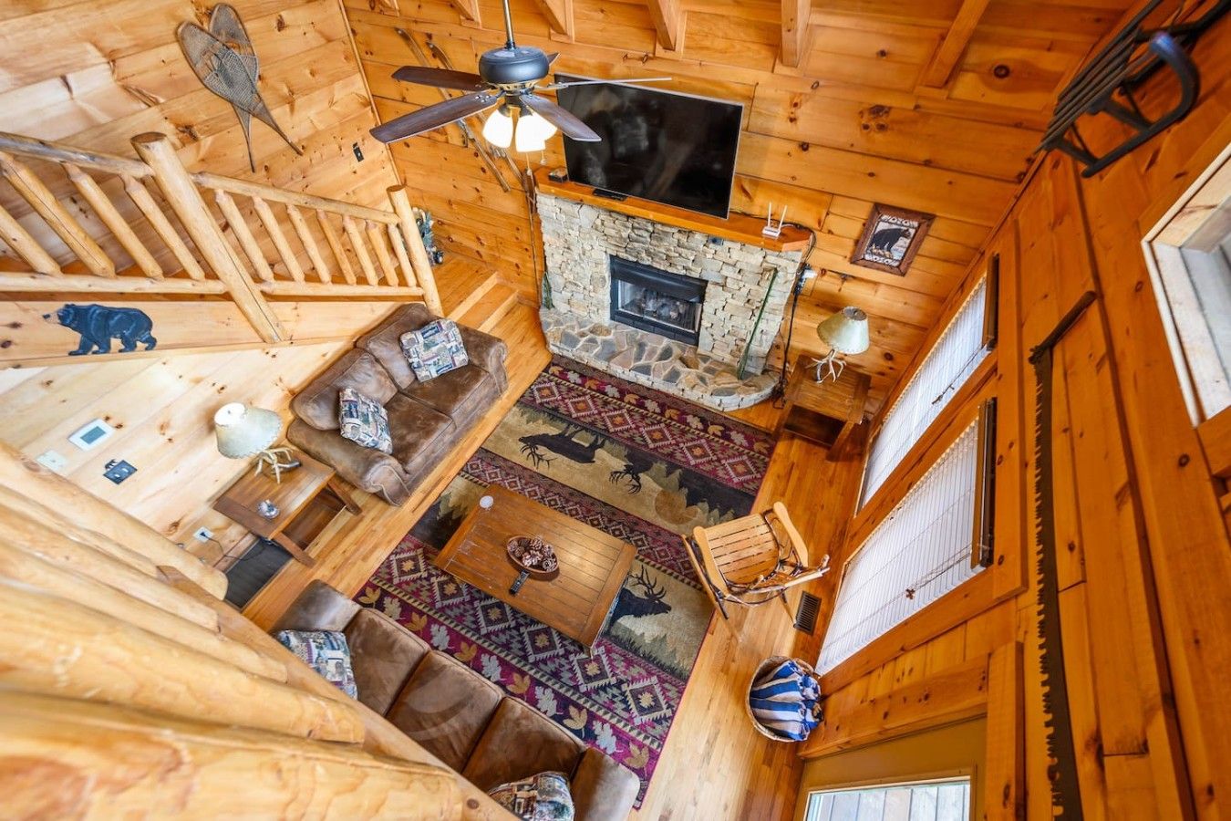 L’intérieur d’un chalet en bois, avec une cheminée en pierre, un ventilateur de plafond, un téléviseur et une luge.