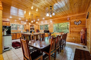 L’intérieur d’un chalet en bois comprend un coin repas, une cuisine et de grandes fenêtres.