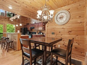 A wooden interior with a dining area, bar, and kitchen. - Peaceful 3BR w/Hot Tub*Theater*Game Room*Privacy! (Sevierville)