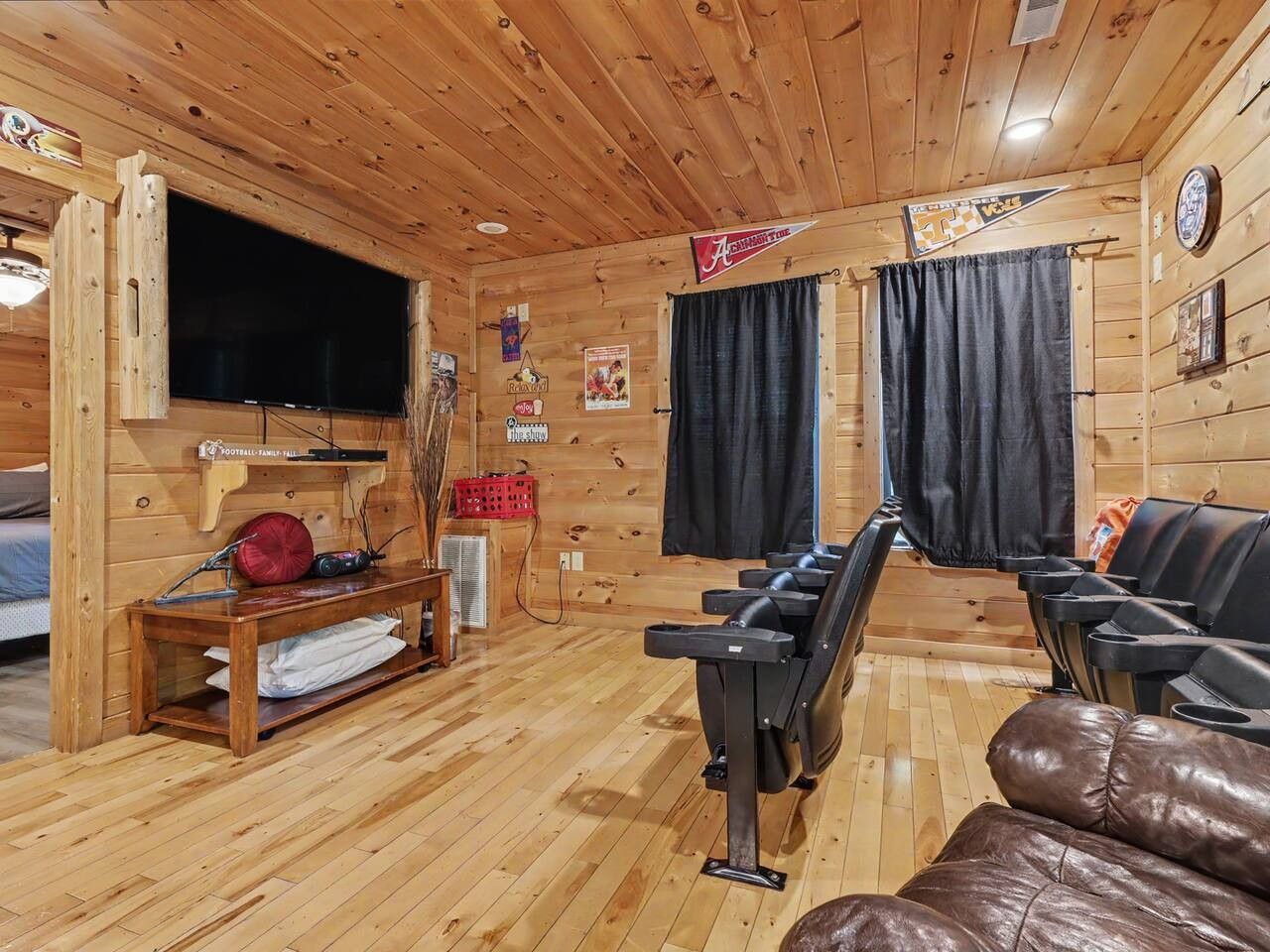 A wooden interior with a television, massage chairs, and a bench with a red pillow.