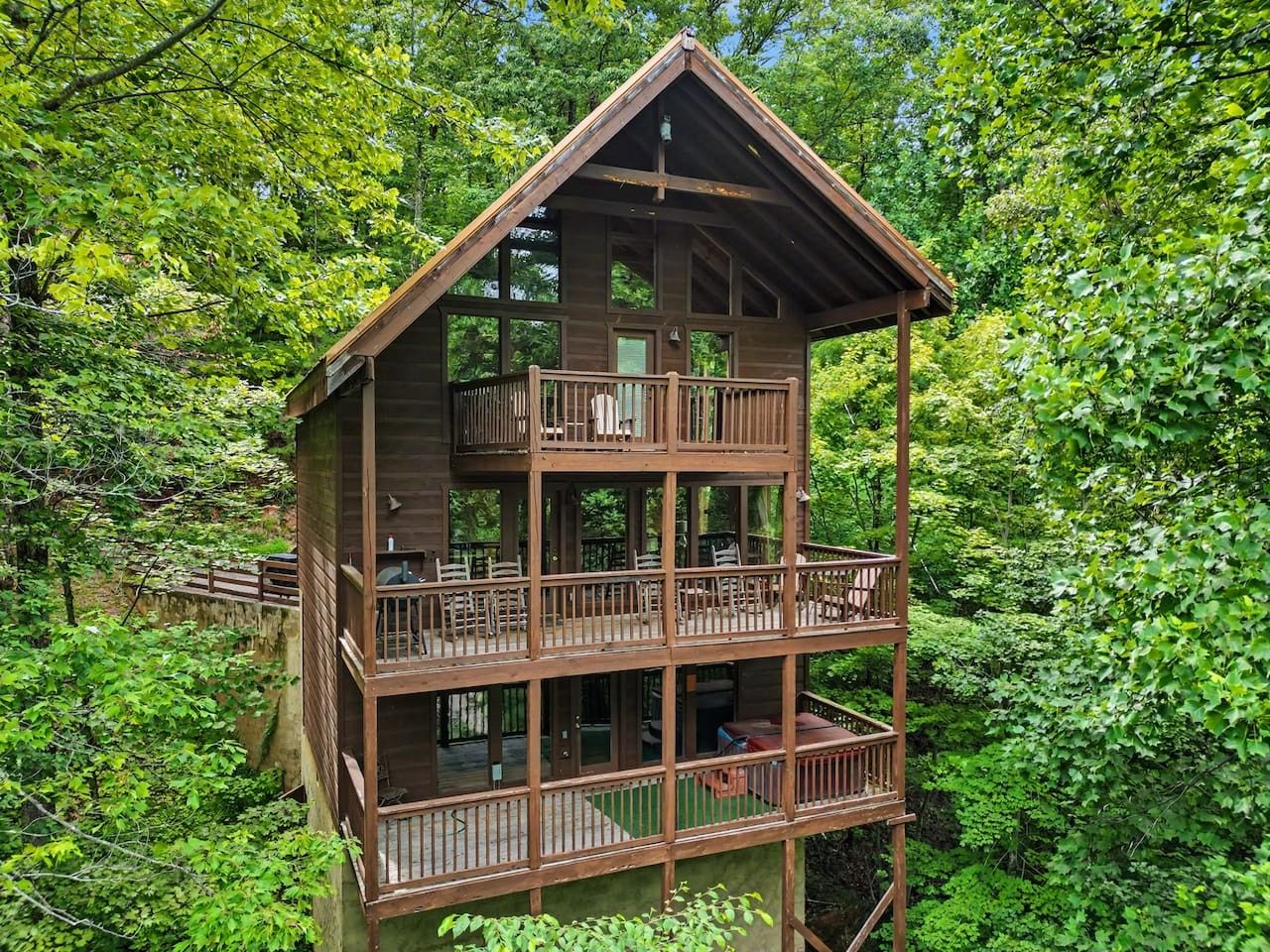 Une cabane en bois à plusieurs niveaux, dotée de balcons et entourée d’une forêt dense.