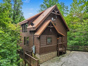 A wooden cabin with a stone foundation, a balcony, and a satellite dish. - Peaceful 3BR w/Hot Tub*Theater*Game Room*Privacy! (Sevierville)