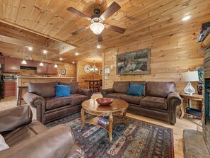 A cozy cabin interior with two leather sofas, a coffee table, and a dining area. - Peaceful 3BR w/Hot Tub*Theater*Game Room*Privacy! (Sevierville)