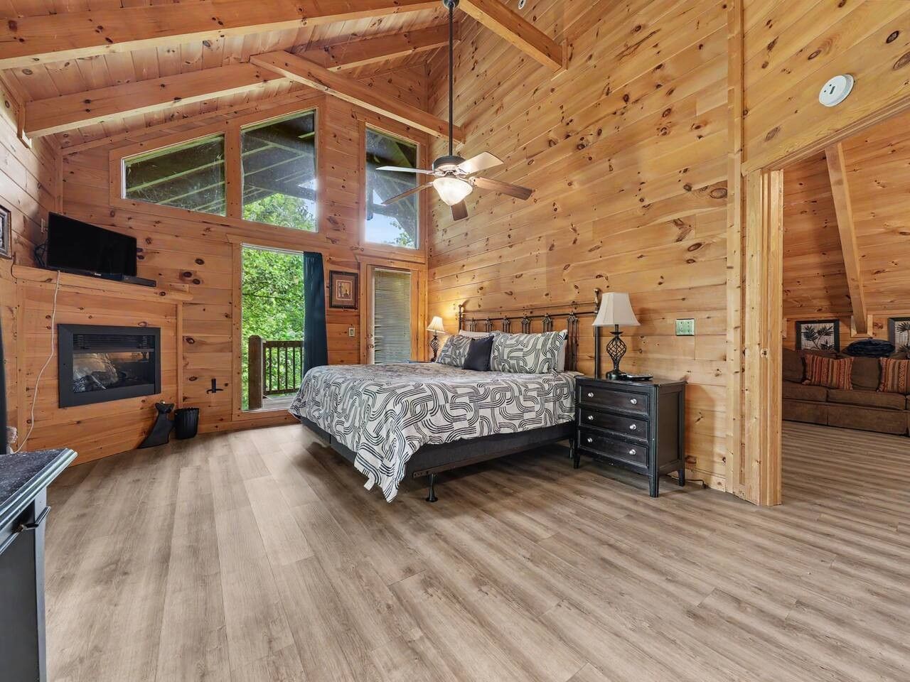 Ein Schlafzimmer einer Holzhütte mit Bett, Schminktisch und Deckenventilator.