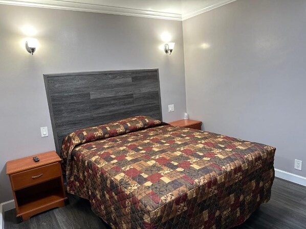 A bedroom with a bed, nightstands, and wall-mounted lights.