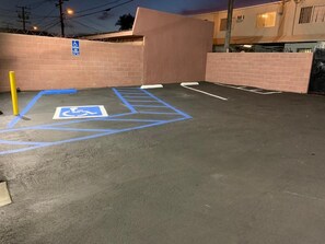Un área de estacionamiento con un espacio reservado para discapacitados, señalizado con pintura azul y el símbolo de una silla de ruedas.