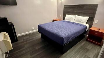 Habitación de hotel moderna con una cama grande, televisión de pantalla plana, mesita de noche y calefacción integrada.