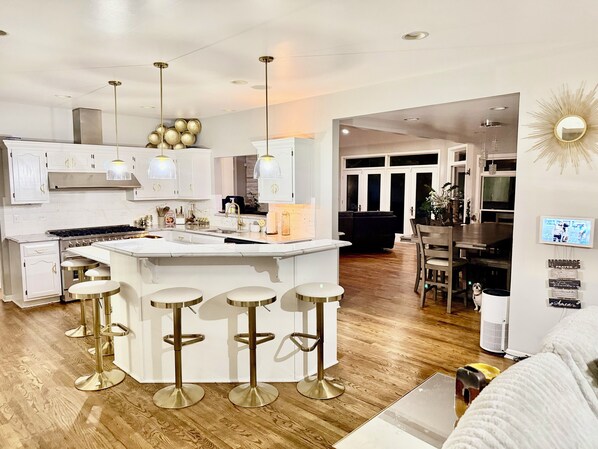 A modern kitchen with a central island, bar stools, and pendant lighting.