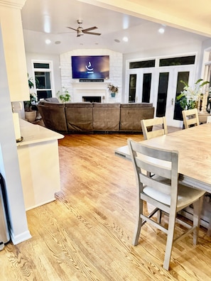 A modern kitchen with a dining area, wooden flooring, and a flat-screen TV mounted above the fireplace. - Spacious 7-bedroom house with AC in wonderful Naperville (Naperville)