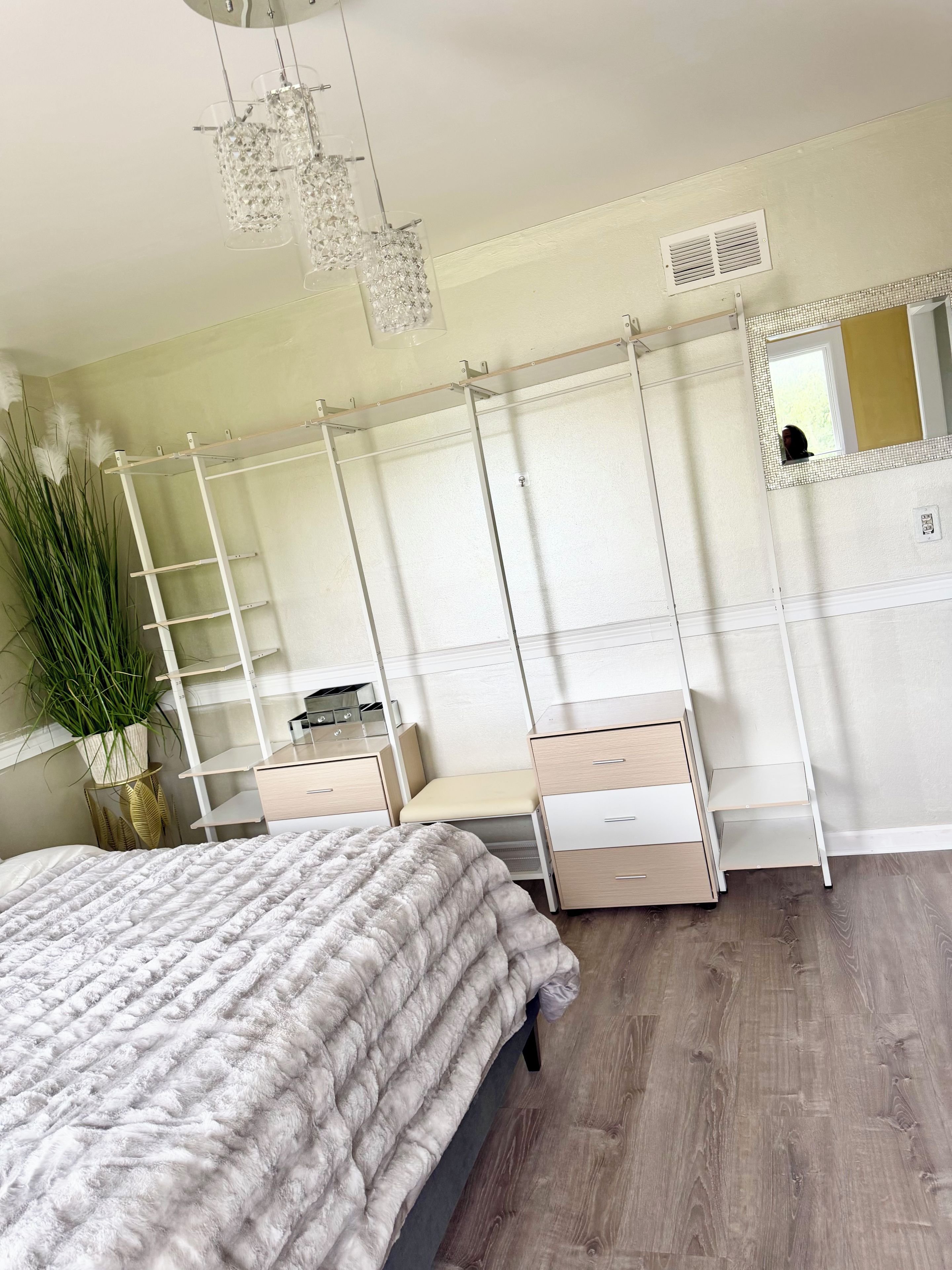 Une chambre à coucher comprenant un lit, des tables de chevet, une commode, un miroir et un luminaire suspendu.