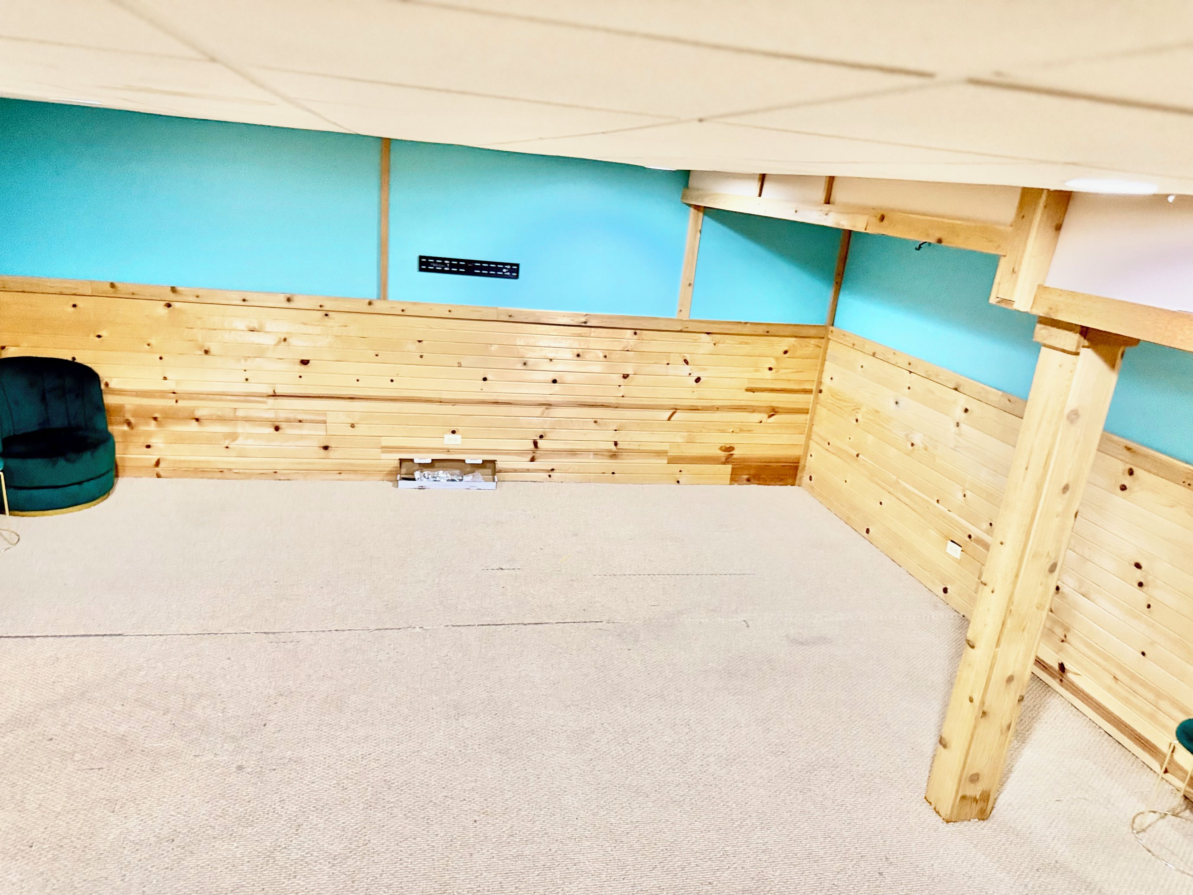 Une pièce avec un lambris en bois, un sol recouvert de moquette et un mur bleu.