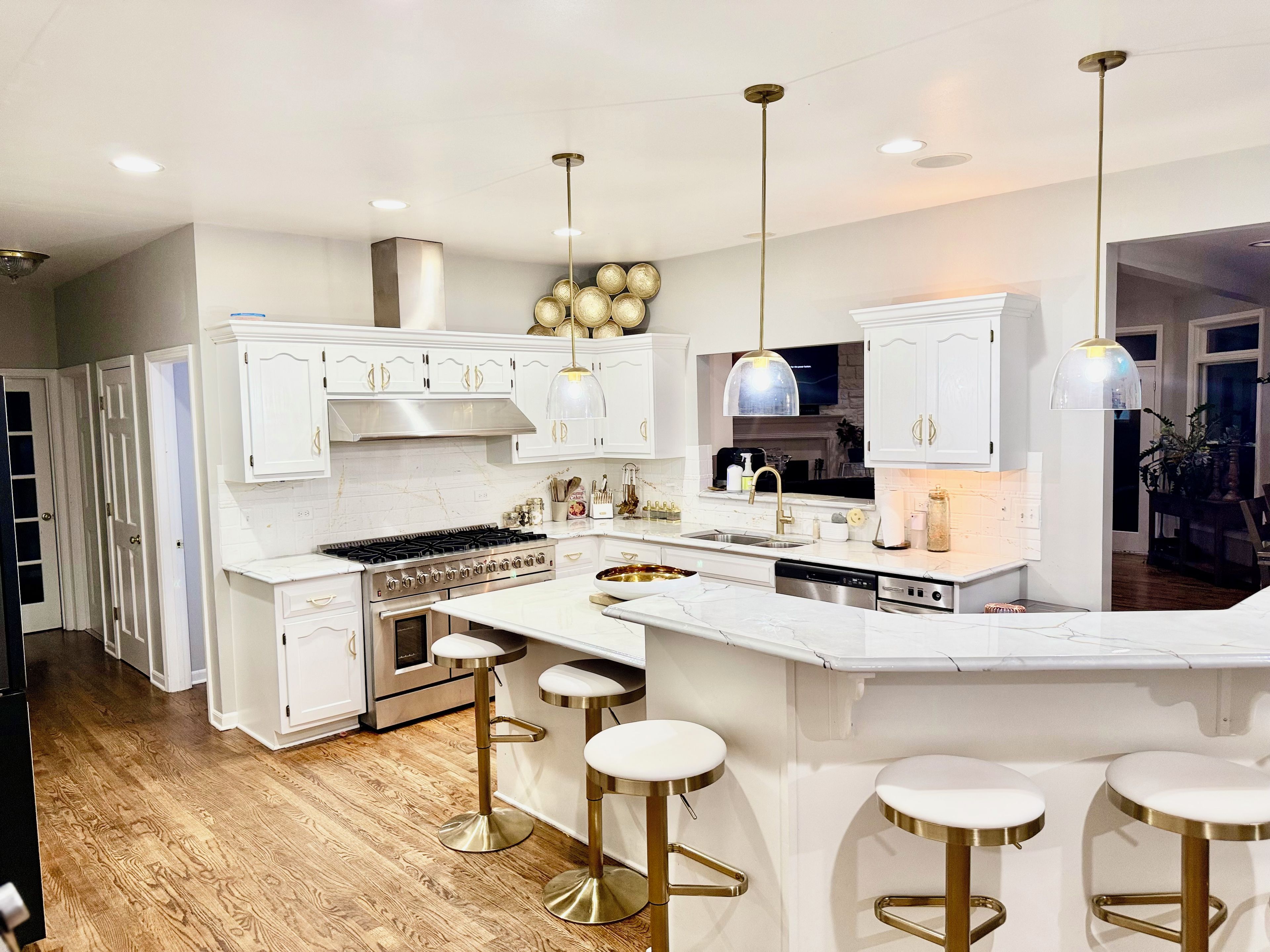 A modern kitchen with white cabinetry, stainless steel appliances, and a central island with stools.